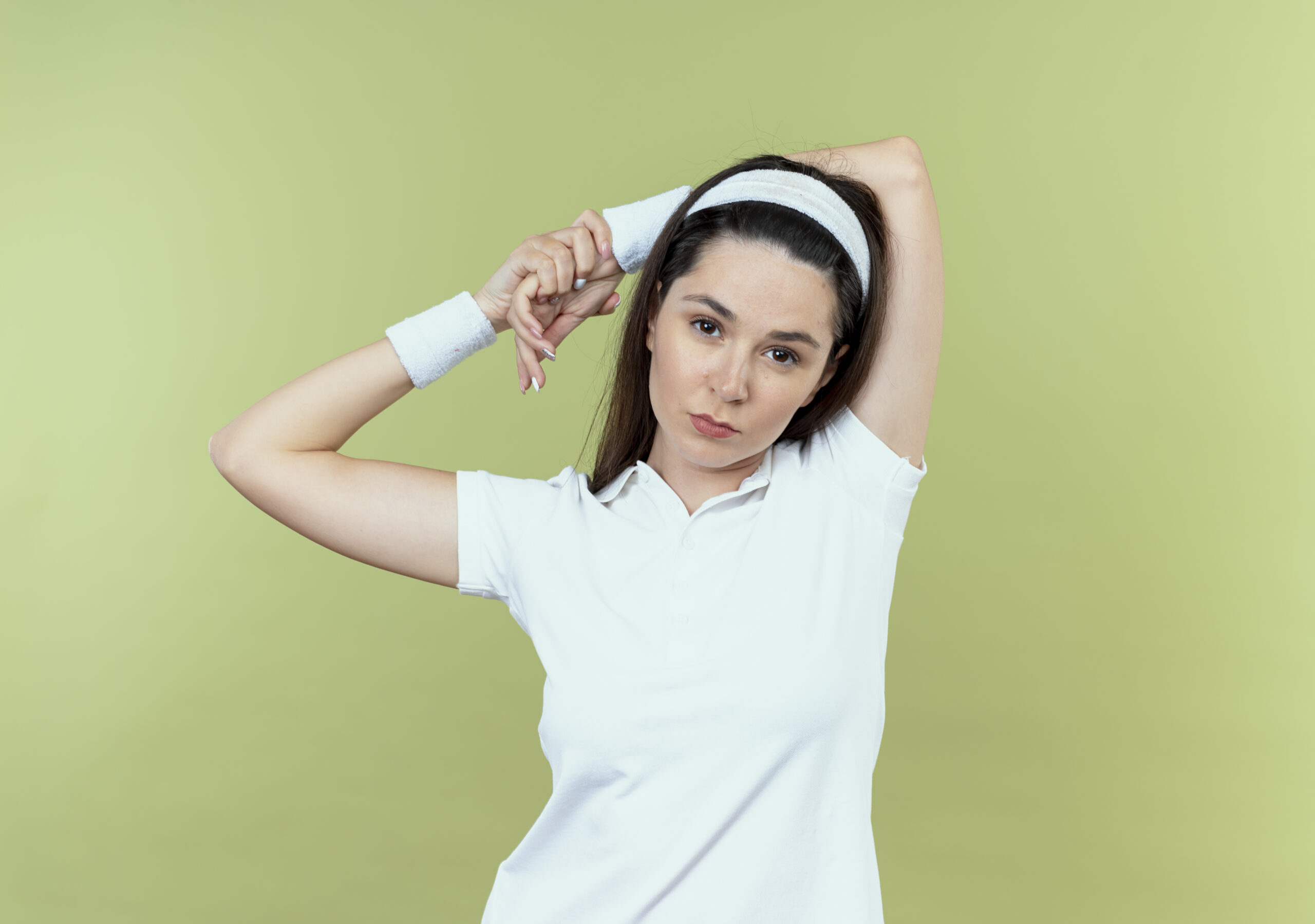 young fitness woman headband stratching her hands looking confident standing light wall scaled